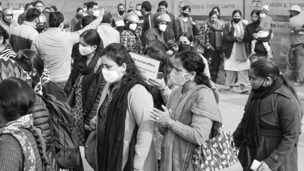 Crowd of people in masks during a protest, highlighting the social impact of unemployment in India.
