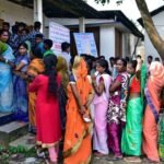 Women voters in colorful sarees waiting to cast their votes in India, highlighting voting rights and participation.