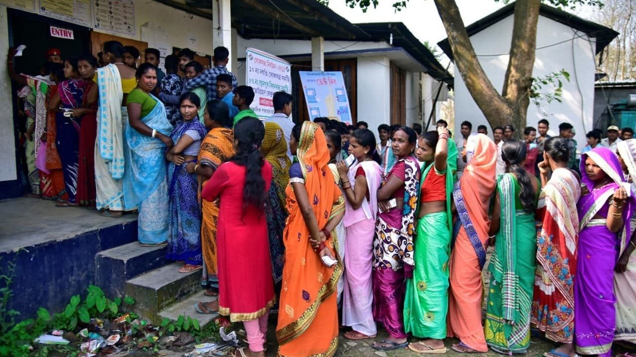 Women voters in colorful sarees waiting to cast their votes in India, highlighting voting rights and participation.