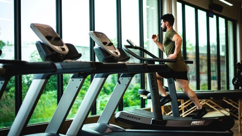 Man running on a treadmill in a gym, highlighting the importance of exercise for heart health.