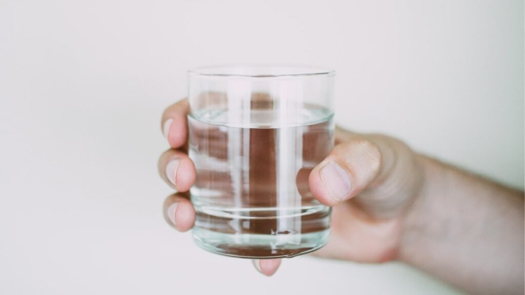 Close-up of a hand holding a glass of water, symbolizing fluid intake management for nocturia treatment.