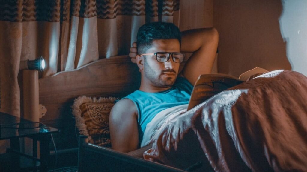 A man reading a book in bed, highlighting the importance of reading books for better sleep.
