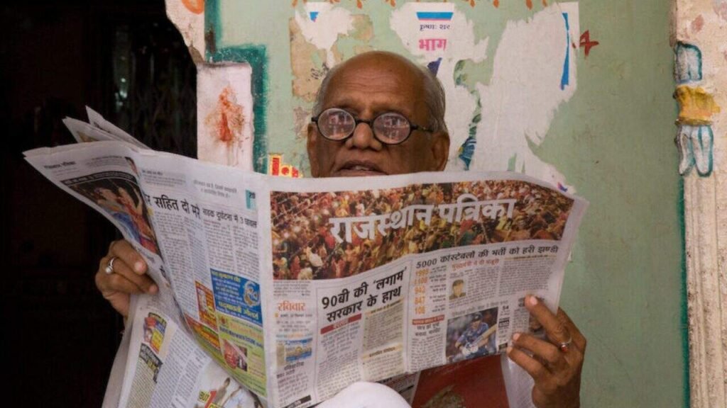 An elderly man reading a newspaper in India, symbolizing traditional media in the context of press freedom.