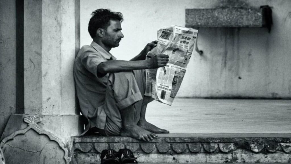 A man reading a newspaper, highlighting the unemployment problem in India.