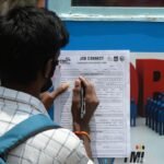 A man filling out a job application form, illustrating the unemployment problem in India.