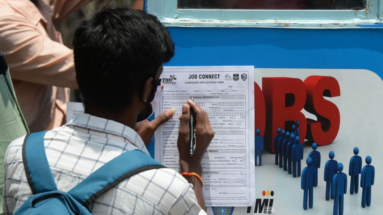 A man filling out a job application form, illustrating the unemployment problem in India.