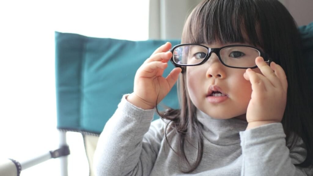 A young child trying on glasses, highlighting the impact of Myopia on children and the need for corrective measures.
